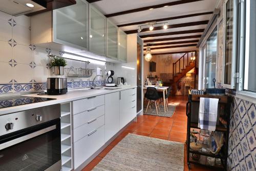 a kitchen with white cabinets and blue and white tiles at Furnas Nook in Furnas