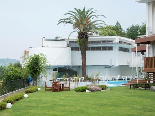 een resort met een palmboom en een zwembad bij Yukai Resort Dogo Saichoraku in Matsuyama