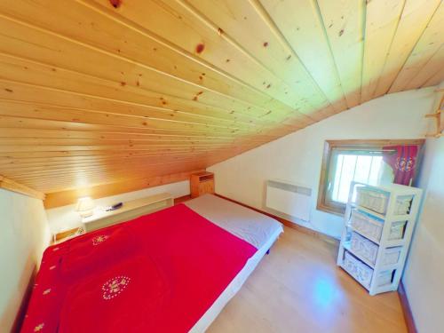 a bedroom with a red bed in a wooden ceiling at Appartement Les Saisies, 1 pièce, 4 personnes - FR-1-594-150 in Hauteluce