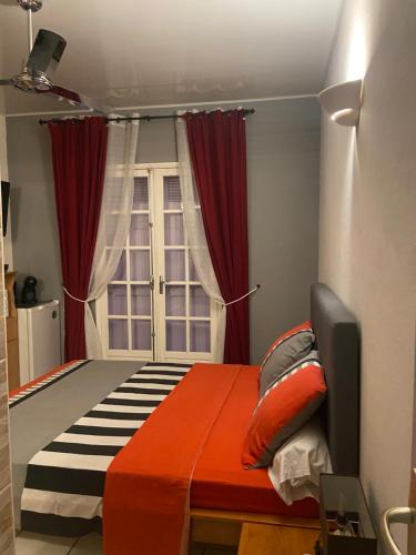 Schlafzimmer mit einem Bett mit roten Vorhängen und einem Fenster in der Unterkunft Happyhome in Saint-Pierre