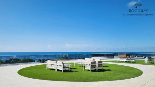 a group of white chairs and tables on a green lawn at O Condominium Beachfront Residences, by Bocobay Aruba in Palm-Eagle Beach