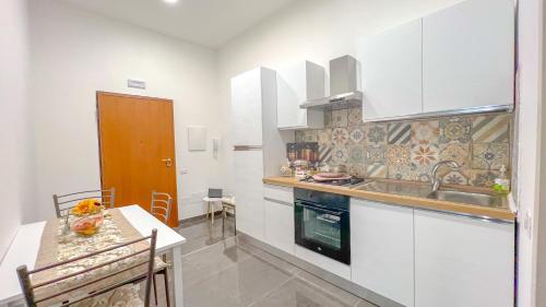 a kitchen with white cabinets and a sink and a table at B&B Ladislaus in Ladispoli