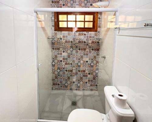 a white bathroom with a shower and a toilet at Chalés Recanto da cachoeira in Monte Verde