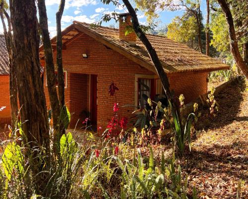 a small brick house in the middle of a garden at Chalés Recanto da cachoeira in Monte Verde