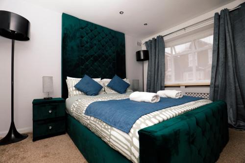 a bedroom with a large bed with a green headboard at Harmony Haven Executive Suite in Nottingham