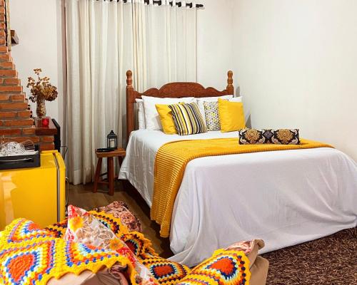 a bedroom with two beds with yellow and white at Chalés Recanto da cachoeira in Monte Verde