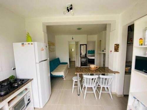 a kitchen with a white refrigerator and a table and chairs at Apartamento em Capão Novo com piscina in Capão da Canoa
