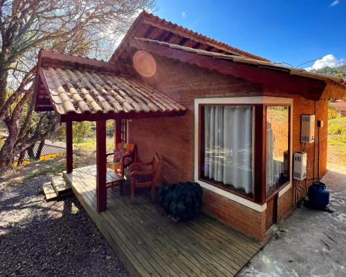 a small cabin with a porch and a window at Chalés Recanto da cachoeira in Monte Verde