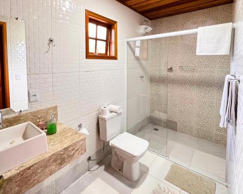 y baño con aseo, lavabo y ducha. en Chalés Recanto da cachoeira, en Monte Verde