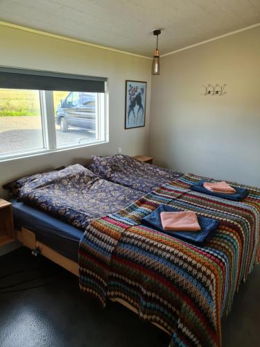 a bedroom with a bed with a blanket and a window at Luxury home surronded with extraordinary nature in Selfoss