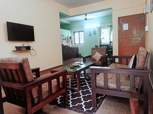 a living room with a table and chairs and a tv at Benirosa Home Stay Apartment 4 in Cansaulim