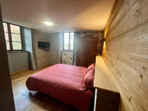 a bedroom with a red bed and a wooden wall at Nouveau appartement 12 personnes - chez mon boucher - in Rouffach
