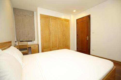 a bedroom with a white bed and a wooden door at Investland in Truc Bach & serviced apartment in Hanoi