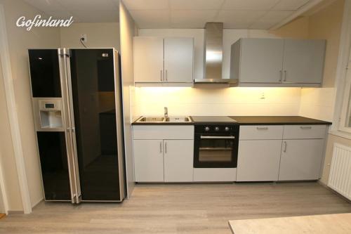 a kitchen with white cabinets and a black refrigerator at Kuukkeli Ivalo Airport Inn in Ivalo