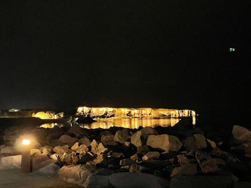 a body of water at night with rocks and a pier at G-1215 apartment in Ytri-Njarðvík