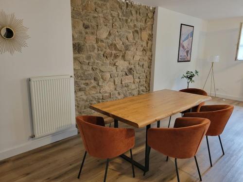 a wooden table and chairs in a room with a brick wall at Cocon Gérardmer à 5min du Lac in Gérardmer