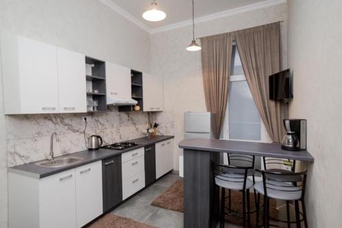 uma cozinha com armários brancos e um balcão preto em Central Accommodation em Chisinau