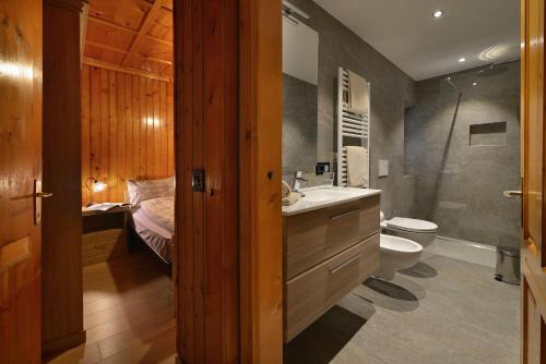 1 cama y baño con lavabo y aseo. en Bait dal Colocator en Livigno