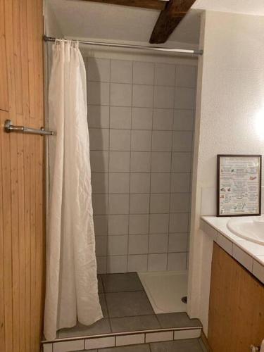 La salle de bains est pourvue d'une douche avec rideau de douche blanc. dans l'établissement La Sorcière in a typical Alsatian house, à Rouffach