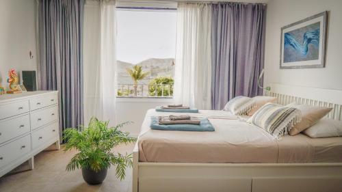 a bedroom with a bed with pillows and a window at Beachfront Haus Meer in the heart of Arguineguin in Arguineguín