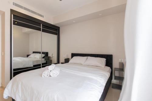 1 dormitorio con 1 cama blanca grande y toallas. en O&O Group - Luxury Tower/parking/Shopping Mall/2BR en Qiryat Ono