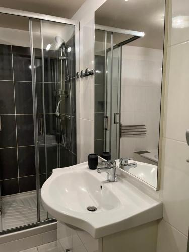 une salle de bain blanche avec un lavabo et une douche dans l'établissement Gîte Laurymoor - Normandie, à Acquigny