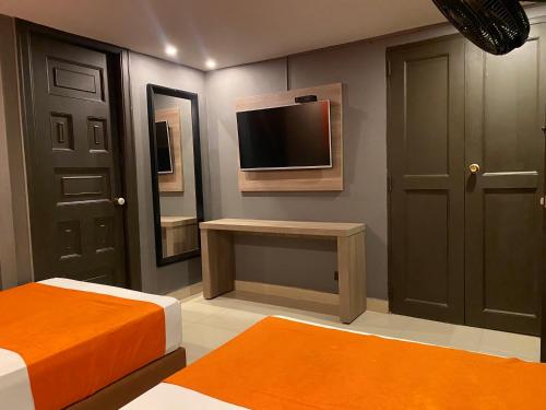 um quarto com duas camas e uma televisão na parede em Hotel Latino Medellín em Medellín