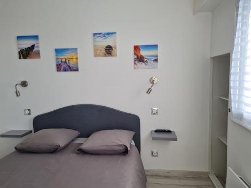 - une chambre dotée d'un lit avec 4 photos sur le mur dans l'établissement LES PIEDS DANS L'EAU - Accès direct à la plage, à Bernières-sur-Mer