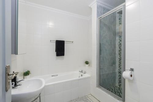 a white bathroom with a sink and a shower at Laguna La Crete 106 in Uvongo Beach