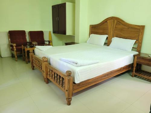 a large wooden bed in a room with chairs at Sea Star Beach Resort Kovalam in Kovalam