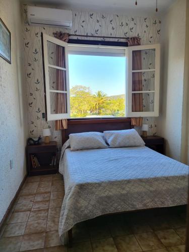 a bedroom with a bed and a large window at Apartamento con Terraza y Parrillero in Piriápolis
