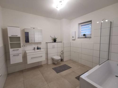 a white bathroom with a toilet and a sink at LOOT: Moderne Wohnung / Zentral in Kitzingen
