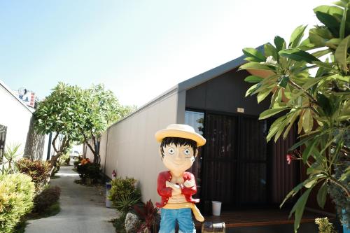 a statue of a person wearing a hat standing in front of a building at Koppie Inn in Xiaoliuqiu