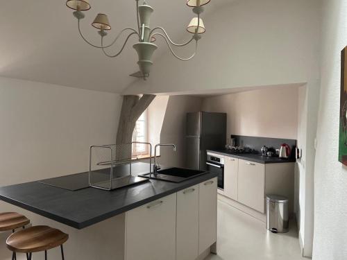 une cuisine avec des armoires blanches et un comptoir noir dans l'établissement Le Loft, à Avallon