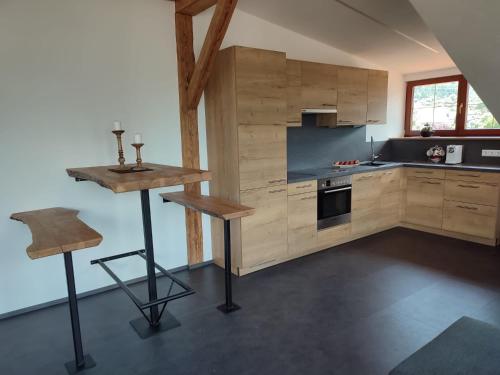 cocina con armarios de madera, mesa y taburete en Ferienwohnung Buchacher, en Dölsach