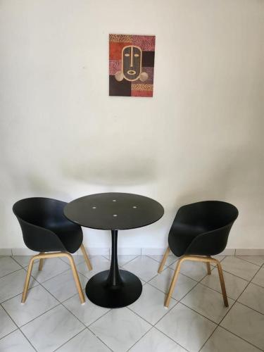 a table and two chairs sitting next to a wall at Résidence DENGUELE Studio in Saint-Laurent du Maroni