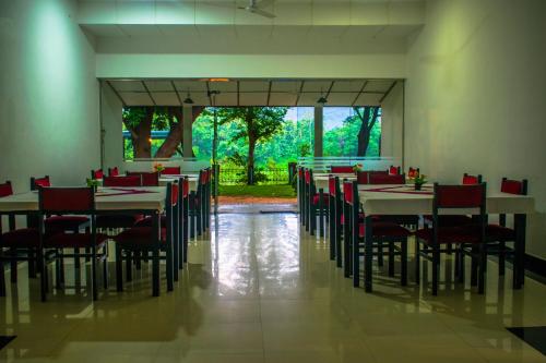 a dining room with tables and chairs and a large window at New Rest House Inn in Mahiyangana