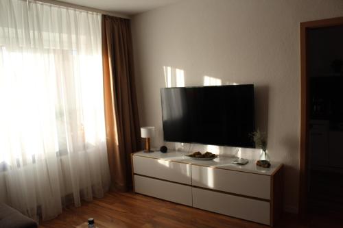 una sala de estar con TV de pantalla plana en una cómoda en haustierfreundliche Ferienwohnung Greifenbach, en Geyer