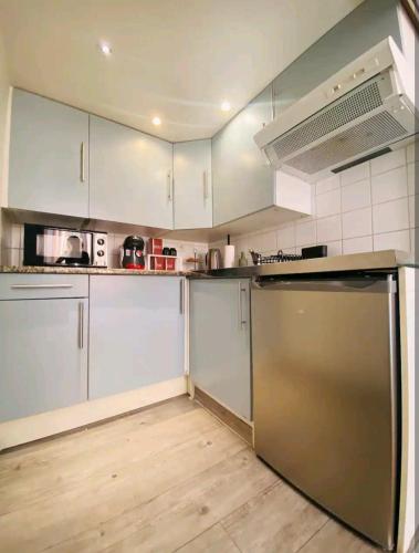 a kitchen with white cabinets and a stainless steel refrigerator at La Parenthèse Enchantée - Belfort Centre proche gare - Fibre Netflix in Belfort