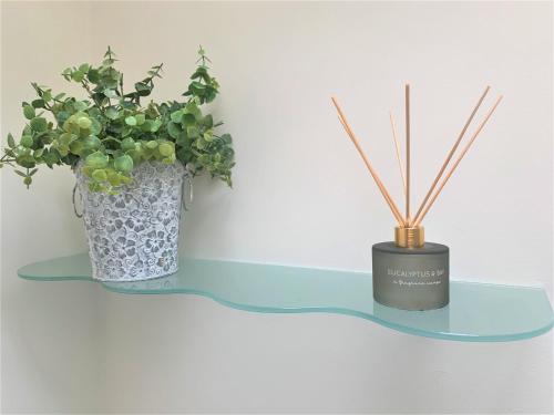 a glass shelf with a vase and a candle on it at Naas 2 Bedroom Back Garden Escape in Naas