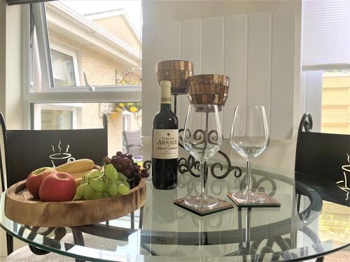 a glass table with a bottle of wine and a bowl of fruit at Naas 2 Bedroom Back Garden Escape in Naas