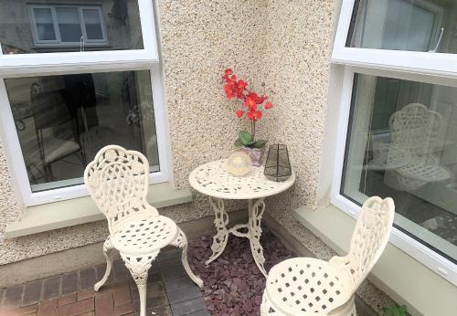 a table and two chairs on a porch with a table and two windows at Naas 2 Bedroom Back Garden Escape in Naas