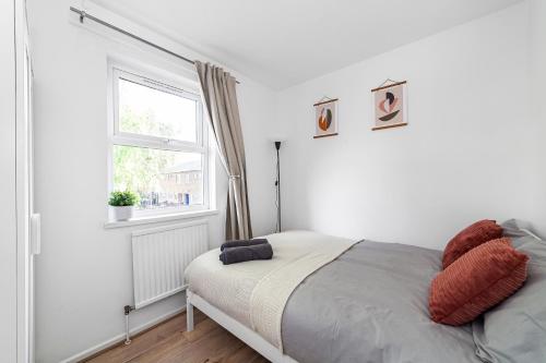 a white bedroom with a bed and a window at Arte Stays - 3-Bedroom Bright House London, Haggerston, Garden, Parking, 8 min walk to Haggerston Station, weekly or monthly stays, serviced accommodation - 7 guests in London