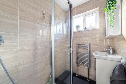 y baño con ducha y lavamanos. en Arte Stays - 3-Bedroom Bright House London, Haggerston, Garden, Parking, 8 min walk to Haggerston Station, weekly or monthly stays, serviced accommodation - 7 guests, en Londres