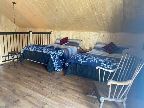 una habitación con 2 camas y una silla en una cabaña en LE JAZZ- Chalet rustique/chic avec SPA en Notre-Dame-Des-Bois
