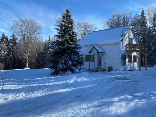 a white house in the snow with a christmas tree at LE JAZZ- Chalet rustique/chic avec SPA in Notre-Dame-Des-Bois