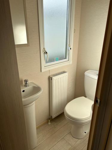 baño con aseo y lavabo y ventana en Beachcomber, A Modern caravan with CH and DG, Smart tv in every room and private broadband, en Rhyl