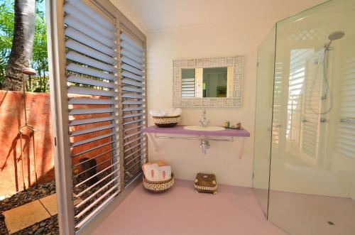 a bathroom with a sink and a shower with a mirror at Sejala Beach Huts in Mission Beach