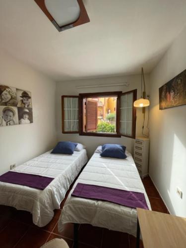 two beds in a room with a window at Lourdes 1 casa compartida solo con la anfitriona in Breña Baja