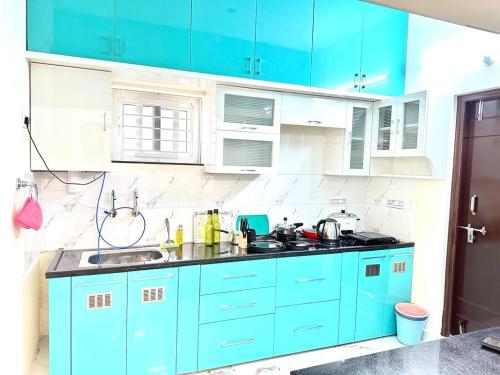 a blue kitchen with white cabinets and a sink at KPHB Phase 15 New Stunning 3 BHK - 5th Floor with Private Parking in Hyderabad